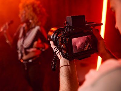 Close up of unrecognizable videographer holding camera and filming music video for jazz band copy space