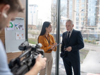 Business talk. Young asian reportercussing work issues while standing next to grey-haired man